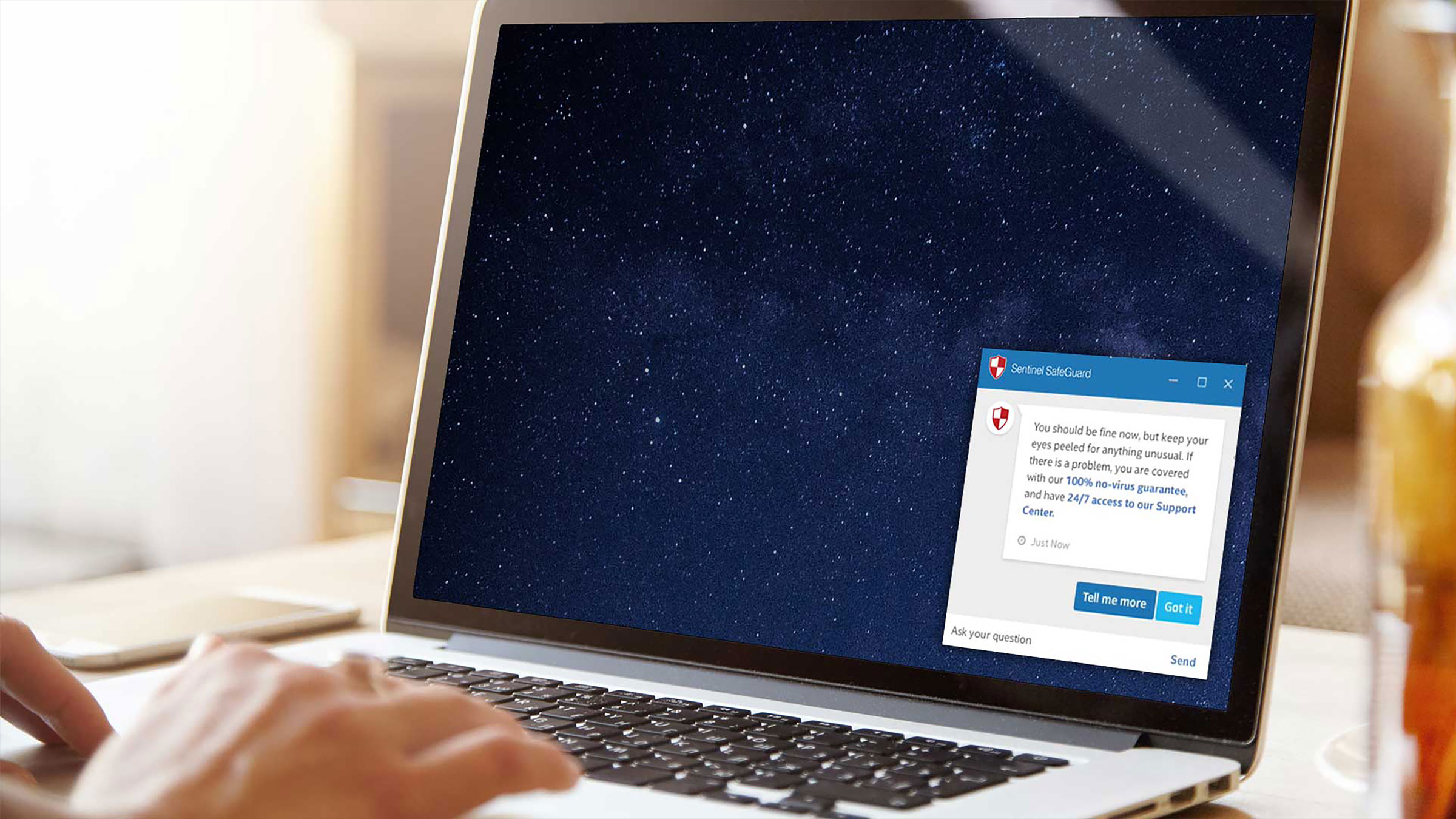 McAfee dashboard on laptop with user writing in notebook